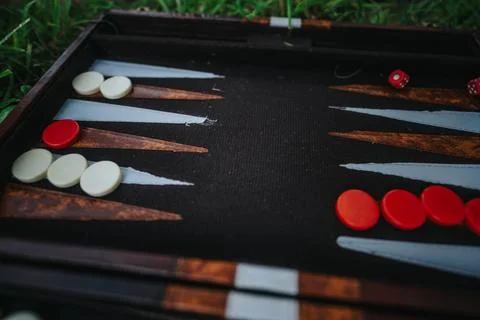 Backgammon board with red and white pieces in a garden setting Stock Photos