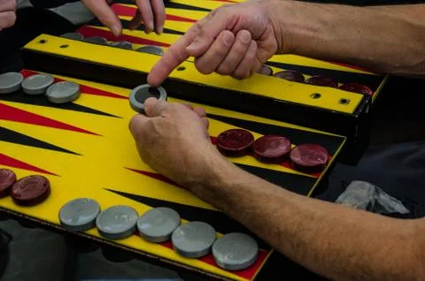 Backgammon game, chips, dice for the game, players at the playing table Stock Photos