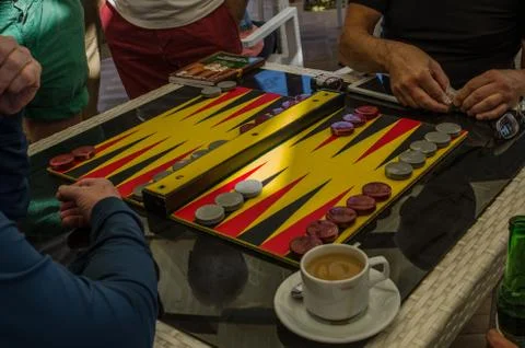 Backgammon game, chips, dice for the game, players at the playing table Stock Photos