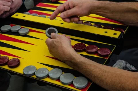 Backgammon game, chips, dice for the game, players at the playing table Stock Photos