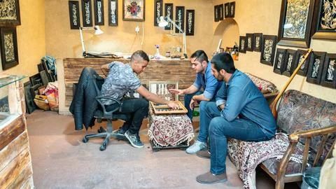 Backgammon in Iran: young men playing takhteh nard in a handicraft shop Stock Photos