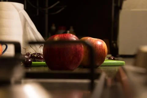 Background apples and cherries on on the kitchen table with a gas stove Stock-Fotos