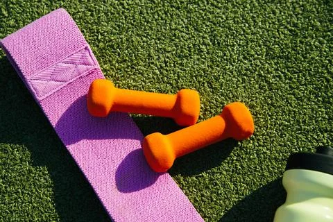 On the background of artificial grass there is a mat, a bottle, a fitness ela Stock Photos