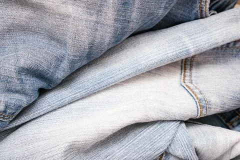 Background, backdrop of many folded old blue jeans denim, second hand clothes Stock Photos