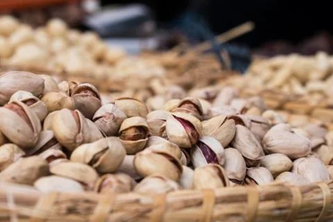 Background of basket of pistachios without shells on market, selective focus Stock Photos