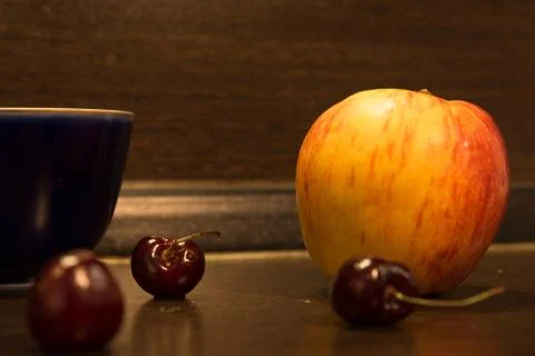 Background big apple and three cherries on the kitchen table Stock Photos