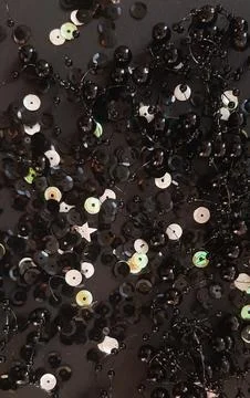 Background  of black and light sequins and a string of black beads on a black ba Stock Photos