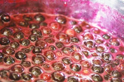 Background with black currant jam boiling in a saucepan Stock Photos