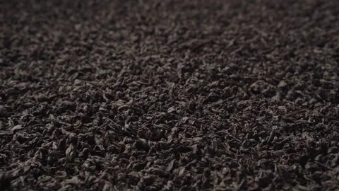 Background of black fanning or broken loose leaf tea slowly rotating. Close-up Stock Footage 240738078