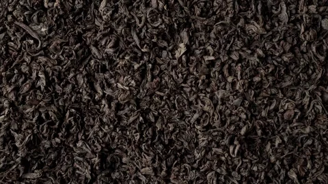 Background of black fanning or broken loose leaf tea slowly rotating. Close up Stock Footage 240738200