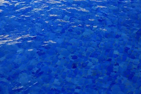 The background is blue water in the pool with waves and glare of light Stock Photos