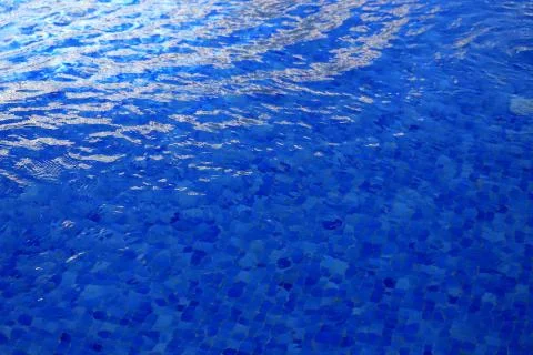 The background is blue water in the pool with waves and glare of light Stock Photos