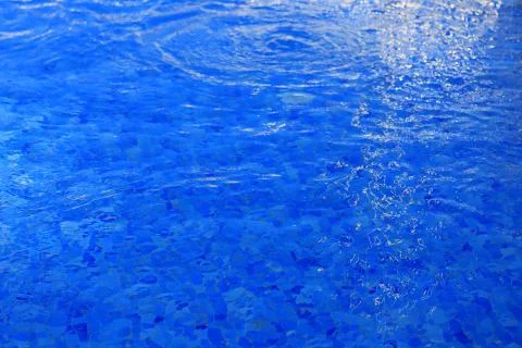 The background is blue water in the pool with waves and glare of light Stock Photos