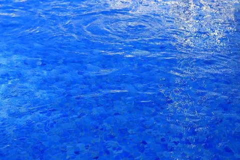 The background is blue water in the pool with waves and glare of light Stock Photos