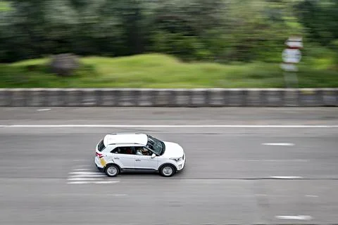 Background blur , selective focus, pan image of a fast moving white car on Pu Stock Photos