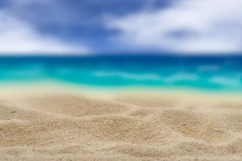 Background. Clean sand on a background of the blurry turquoise sea. Stock Photos
