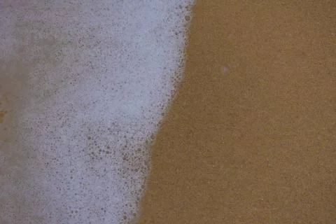 Background close-up of ocean waves rolling on the sand on the beach, with a s Stock Photos