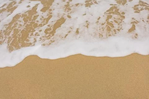 Background close-up of ocean waves rolling on the sand on the beach, with a s Stock Photos