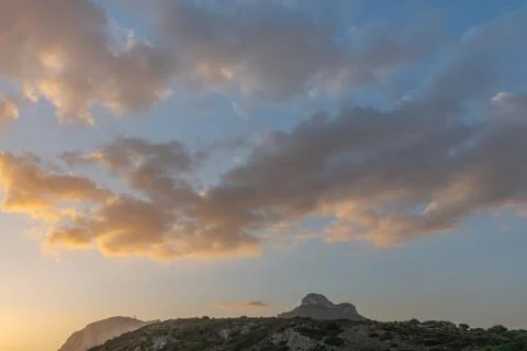 Background clouds in the sky are highlighted by the rising sun. Mountains in the Foto stock