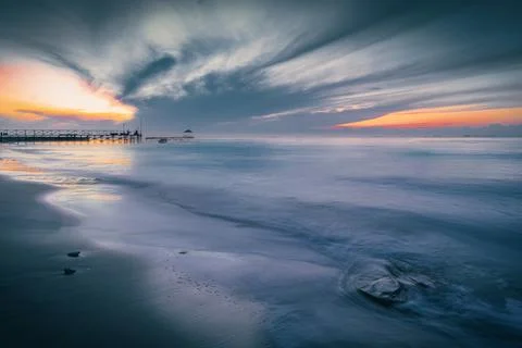 Background of cloudy sunrise on the beach using long exposure. Stock Photos