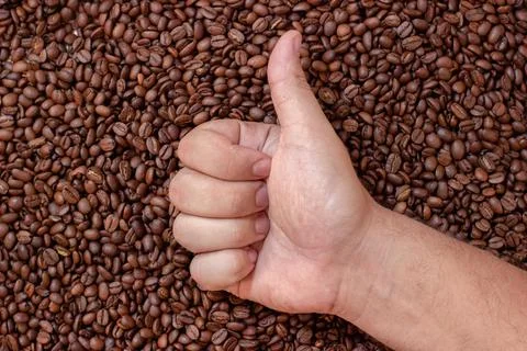 Like on background of coffee beans. A man hand shows thumb up Stock Photos