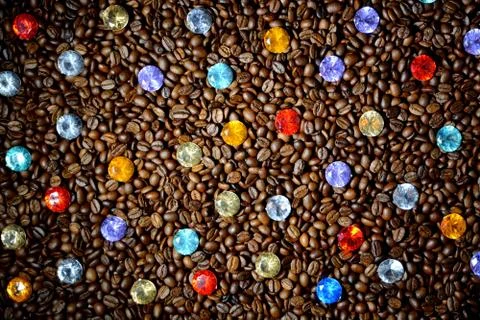 Background from coffee beans with multi-colored stones on a wooden table. Stock Photos