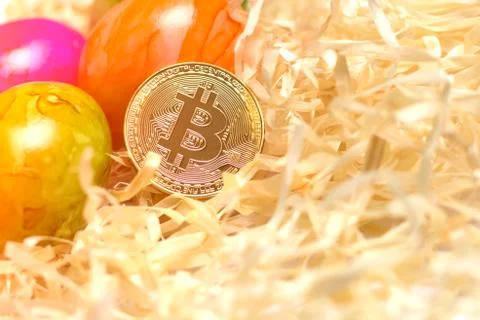 Background of colored eggs and bitcoin on packing straw. Closed up. Consept - Stock Photos