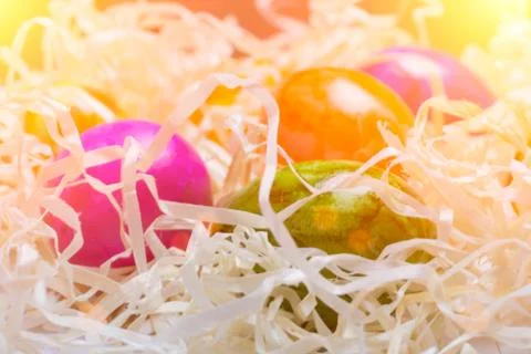 Background of colored eggs on packing straw. Closed up. Easter. Toned with su Stock Photos