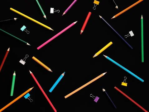 Background colored pencils in chaotic order, paper clips on black background Stock Photos