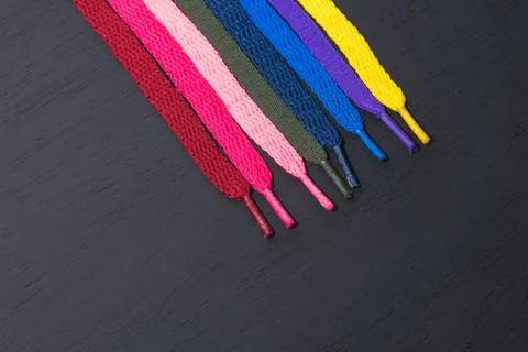 Background of colored shoelaces on black wood, arranged diagonally, concept o Stock Photos