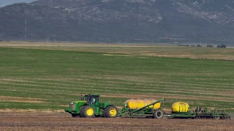 Background compression as aerial circles tractor seeding spring field Stock Footage 310651408