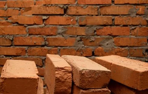 Background consisting of a brick wall and several bricks in the foreground Stock Photos
