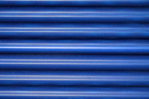 Background created with the foreground of a blue, striated and perforated m.. Stock Photos