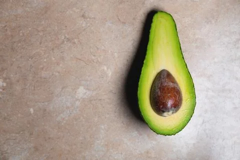 Background. cut avocado in half, with a bone inside, lies on the table. view Stock Photos