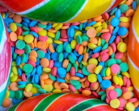 Background from delicious multicolored candy and confetti top view Stock Photos