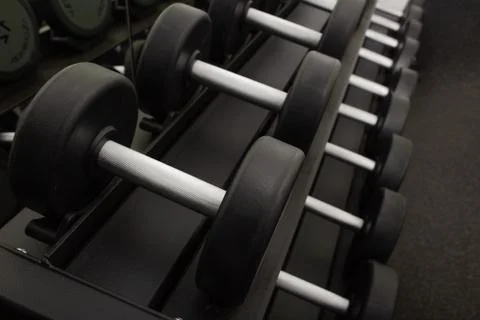 Background of dumbbells on rack in fitness and workout room.Selective focus Stock Photos