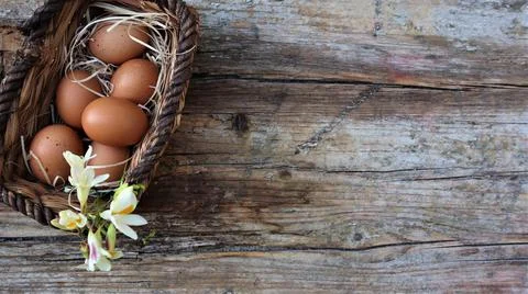 Background easter. A basket with eggs stands on a wooden rustic background. C Stock Photos
