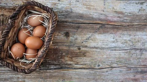 Background easter. A basket with eggs stands on a wooden rustic background. C Stock Photos