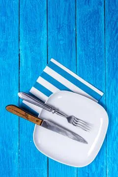 Background with empty squared white ceramic plate, silver fork and old wooden Foto stock