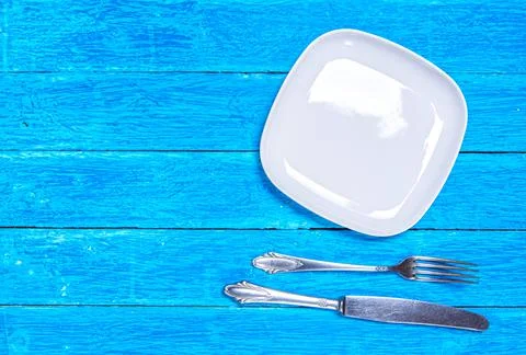 Background with empty squared white ceramic plate, antique silver cutlery on Stock Photos