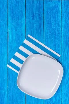 Background with empty squared white ceramic plate on blue wooden boards Stock Photos