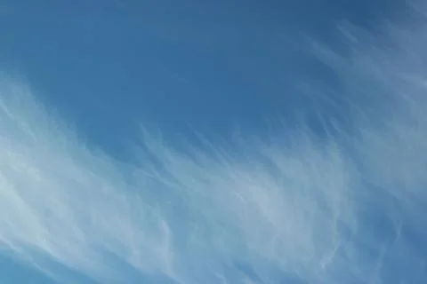 Background featuring a blue sky with winter clouds drifting away in the wind Stock Photos