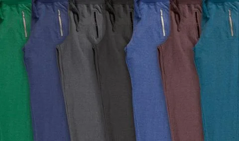 Background with folded set multi-colored jogging pants. Stock Photos