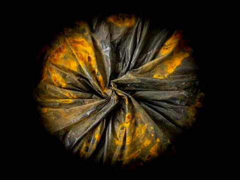 Background in the form of a top view of a black plastic bag stained with rust Stock Photos