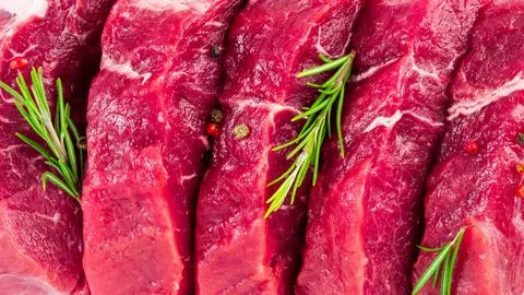 Background of fresh raw sliced beef steaks, garlic, rosemary and seasonings.. Stock Photos