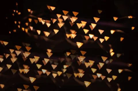 A background with a golden figure bokeh. Triangular unusual lights for decor. Stock Illustration