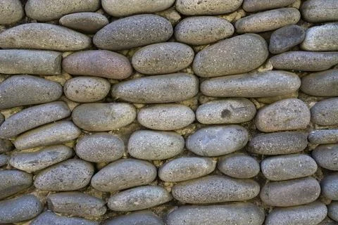 Background of gray stone wall. Stack or pile of stones cemented. Texture or b Stock Photos