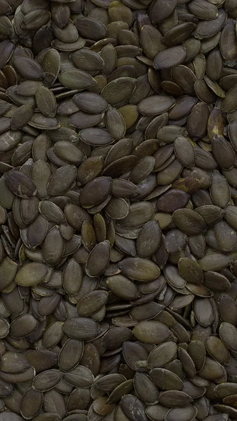 Background of green pumpkin seeds. Vertical video. Stock Footage 310432557