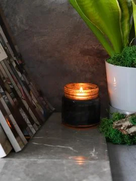 The background image. A burning black candle next to a potted plant. grey Stock Photos