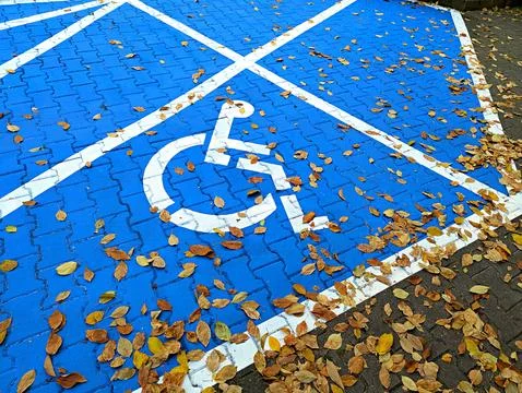 Background image of the disabled person's emblem on asphalt on a blue background Stock Photos